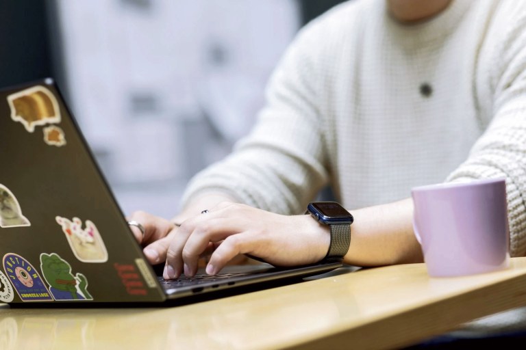 Lähikuvassa nuoren ihmisen kädet kirjoittamassa tietokoneella.