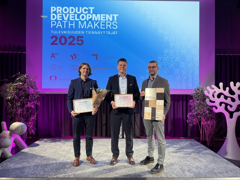 Voittajia palkintojen kanssa lavalla.