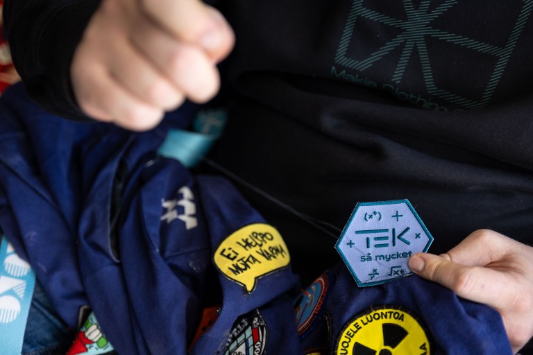 Lähikuvassa merkin ompelua haalareihin.