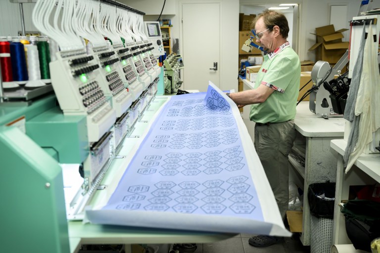 Brodeeraaja irrottamassa kangasta raamista.