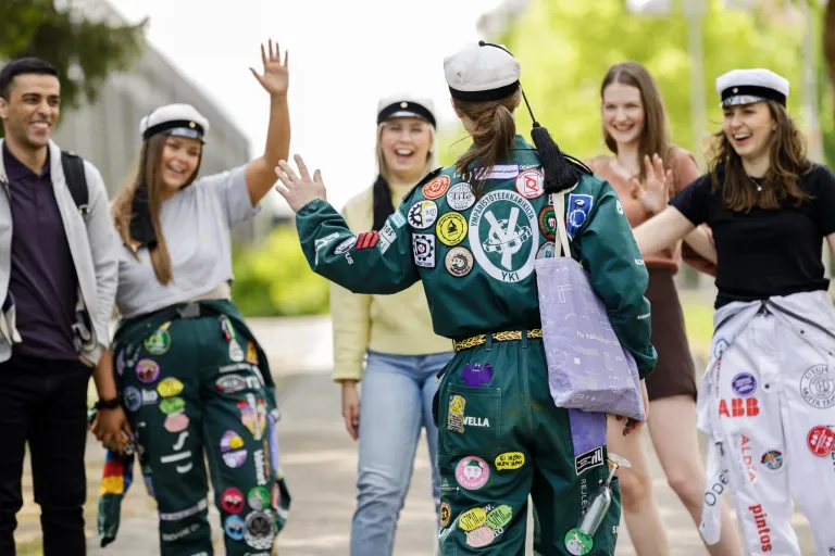 Joukko opiskelijoita tervehtii iloisesti toisiaan.