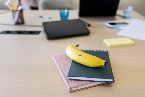 Työpöytä jossa vihkoja, kyniä, kirjoja sekä banaani