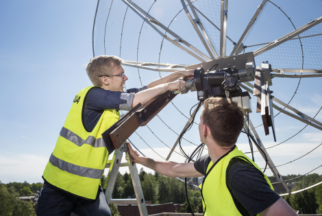 Kaksi henkilöä korjaa satelliittiantennia