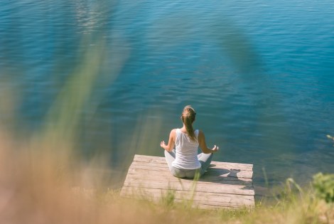 nainen meditoi laiturilla