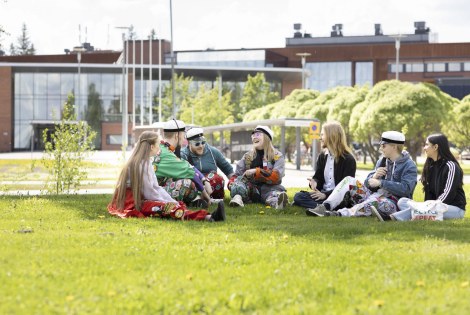 opiskelijoita istuu nurmikolla