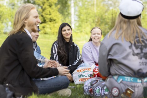 Opiskelijoita istumassa nurmikolla kesäisenä päivänä