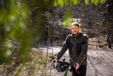 Jussi-Pekka Teini taluttaa pyöräänsä metsätiellä.