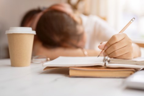 A tired student, a cup of coffee and homework.