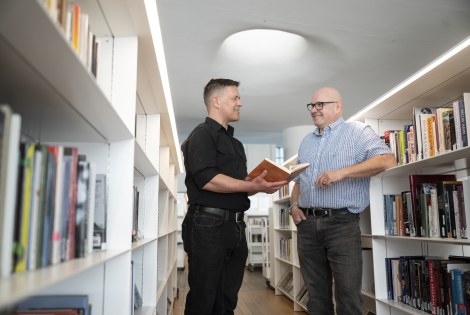 Mikko Hyökki ja Risto Kauppinen juttelevat Oodin kirjahyllyjen välissä.
