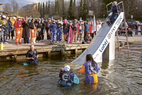 Ihmisiä kerääntyneenä katsomaan, kun opiskelijat laskevat liukumäellä veteen.