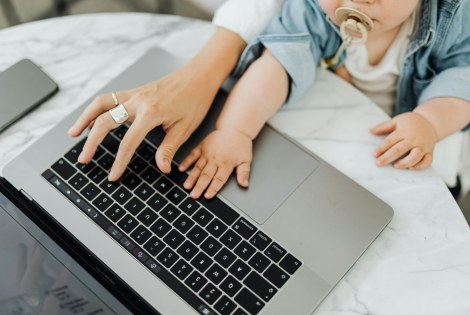 Aikuinen ja vauva yhdessä kannettavan tietokoneen äärellä