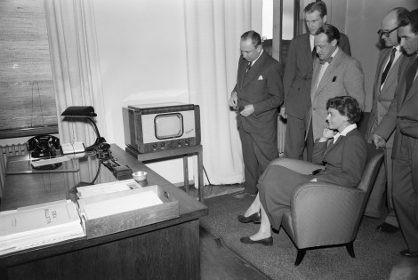 Mustavalkoinen kuva televisiosta ja ihmisistä katsomassa sitä.