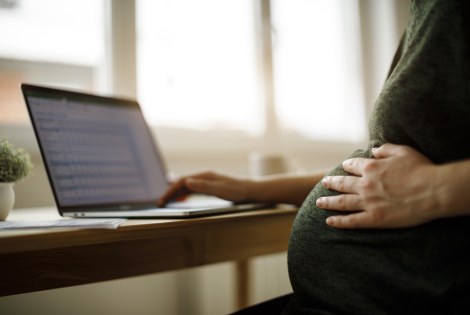 Raskaana oleva henkilö kannettavan tietokoneen ääressä.