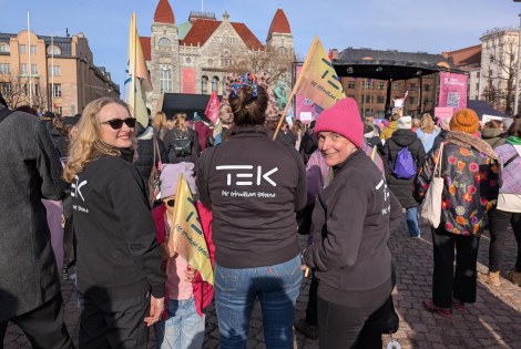 TEKin edustajat seisovat Rautatientorilla, jossa on paljon ihmisiä.