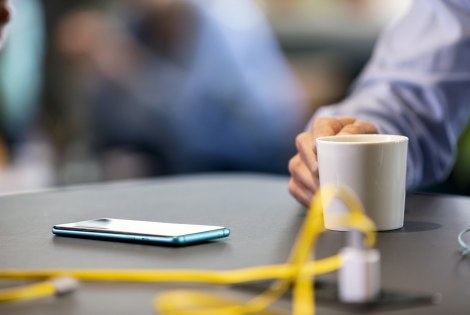 Kahvikuppi ja puhelin pöydällä.