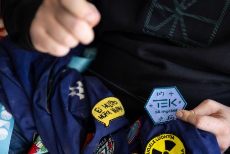 Lähikuvassa merkin ompelua haalareihin.