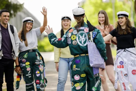 Joukko opiskelijoita tervehtii iloisesti toisiaan.