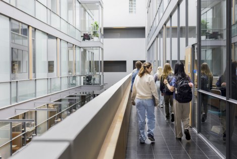 Ihmisiä kävelemässä käytävällä modernissa lasiseinäisessä toimistotilassa