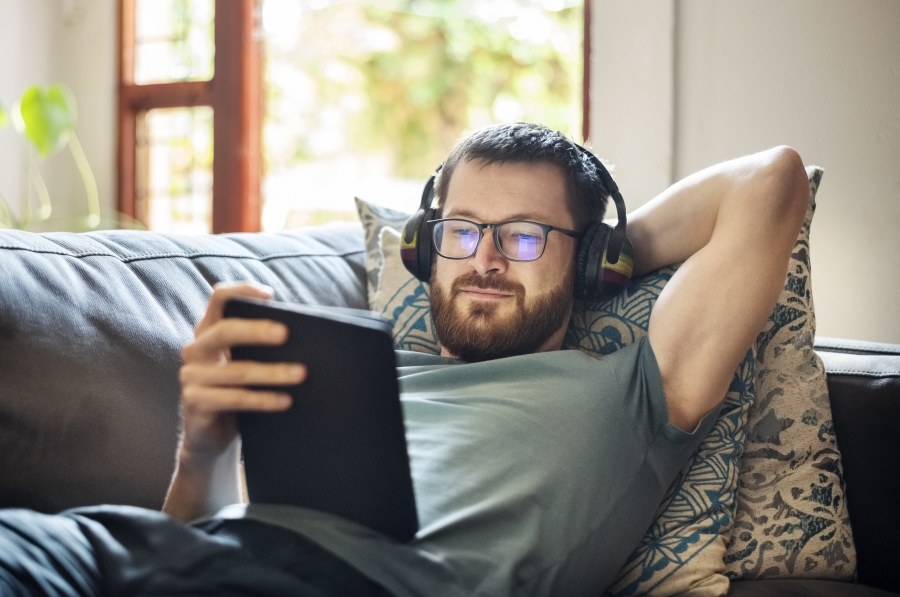 Mies katsoo kuulokkeet päässä tablettia