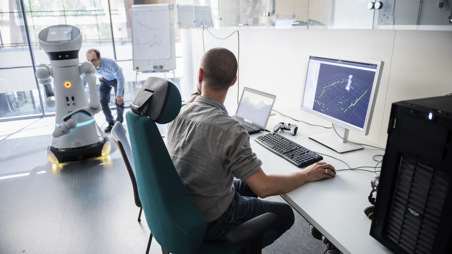 Kaksi henkilöä työskentelee robotin kanssa