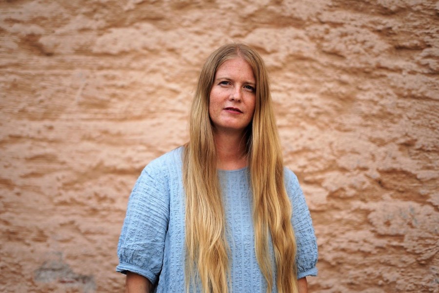 Tiina-Emilia Kaunisto kuvattuna rapattua kiviseinää vasten