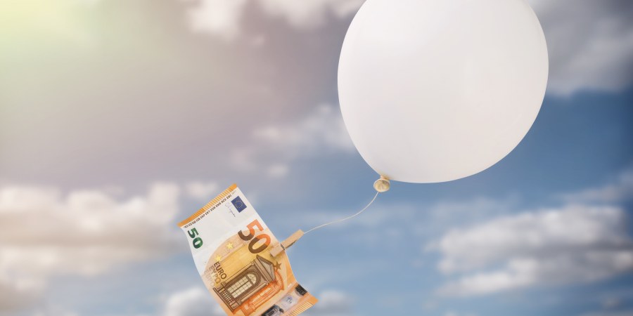 50 euron seteli roikkuu ilmapalloon kiinnitettynä taivaalla.